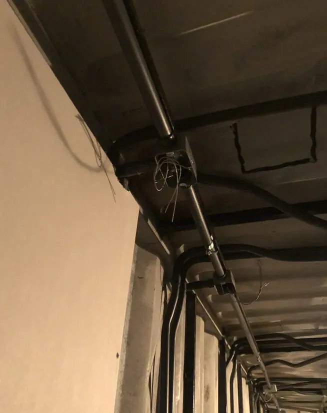 Canalización eléctrica metálica en el techo, junto a una pared