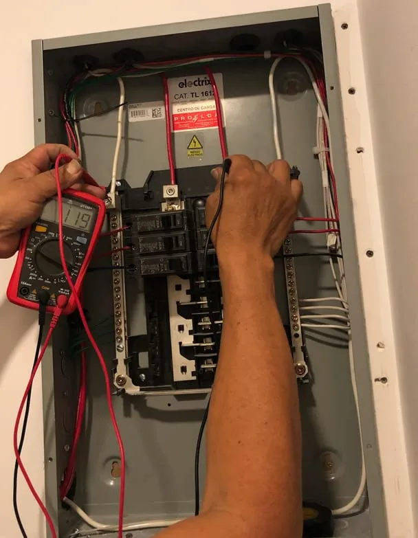Técnico midiendo con un multímetro dentro de un tablero eléctrico