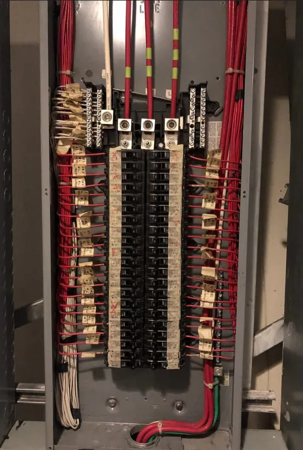 Panel eléctrico con barras de distribución, interruptores y cableado identificado