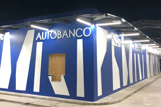 Edificio comercial azul con rótulo y luminarias LED lineales en el exterior, de noche