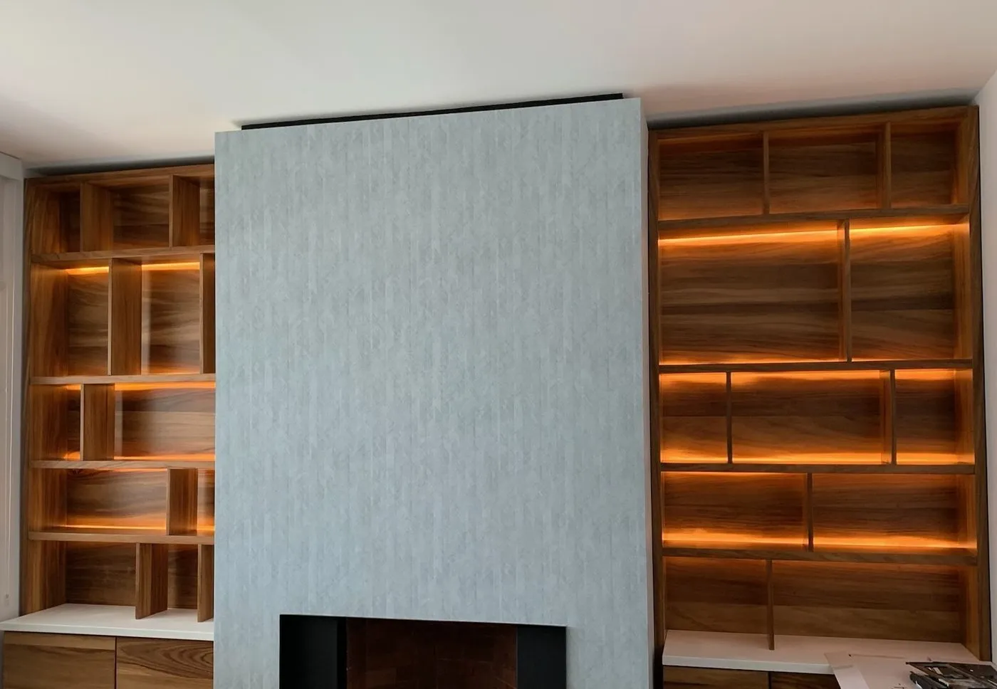 Pared revestida junto a un mueble de madera con iluminación LED