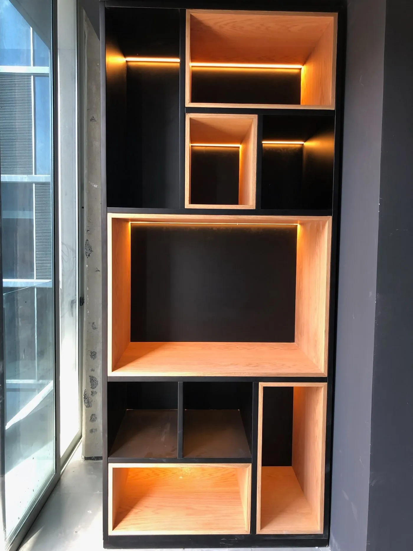 Mueble con nichos iluminados con LED junto a una ventana