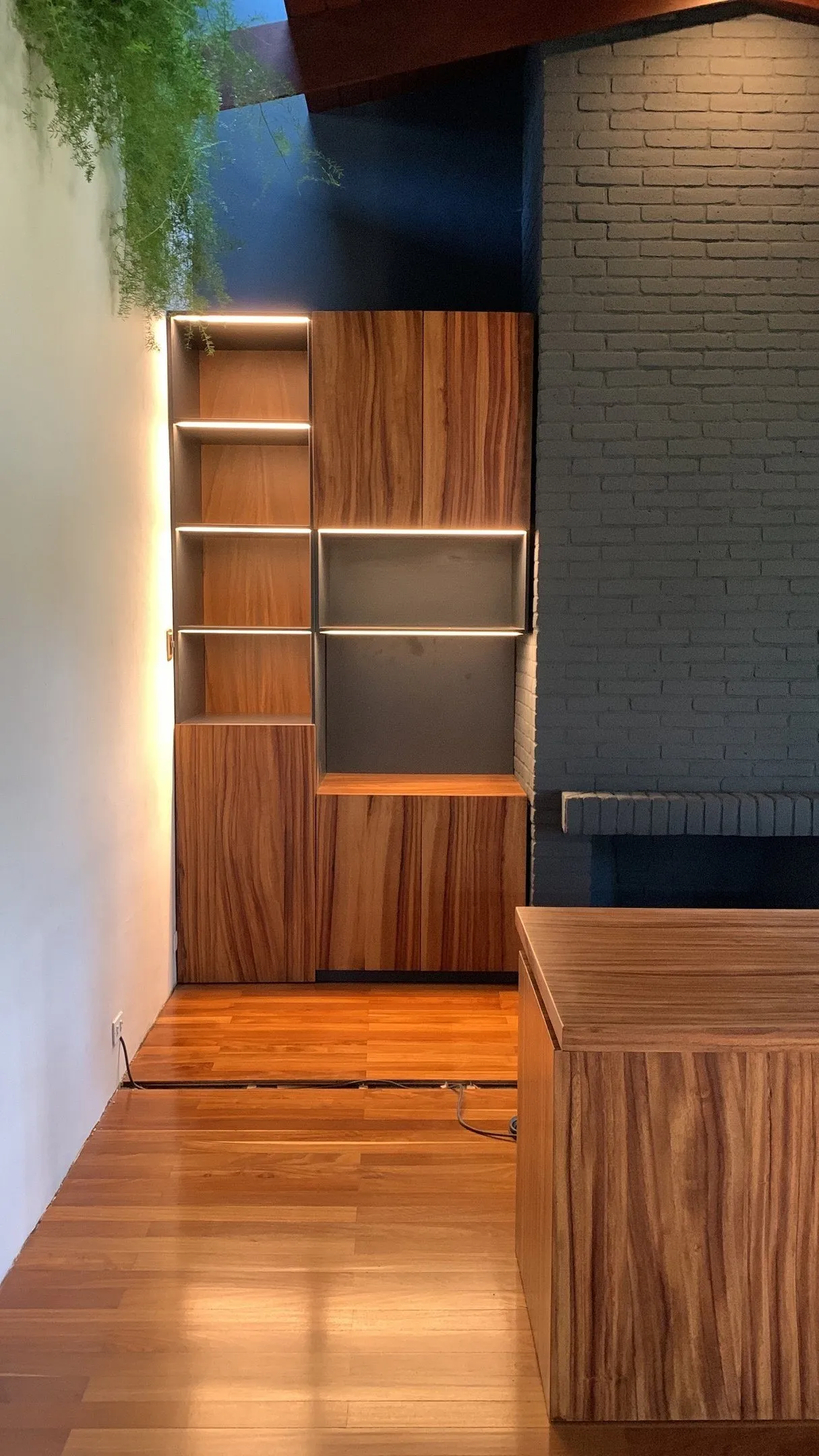 Mueble de madera con iluminación LED junto a una chimenea de ladrillo