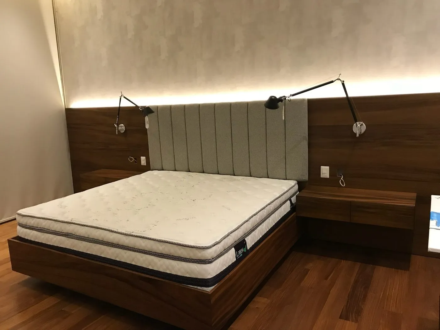 Dormitorio con cabecera tapizada, lámparas de lectura e iluminación LED indirecta en el cielo