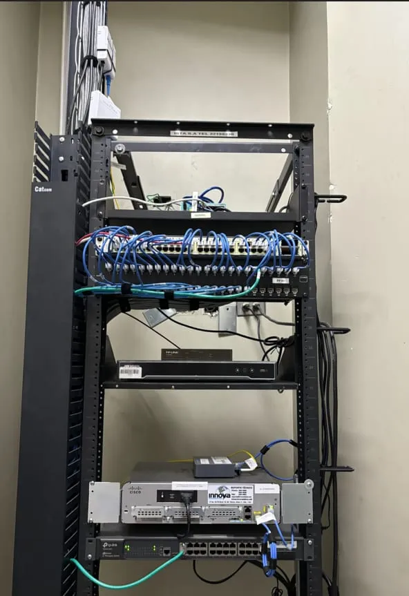 Rack abierto con equipos de red y cableado azul organizado en un cuarto