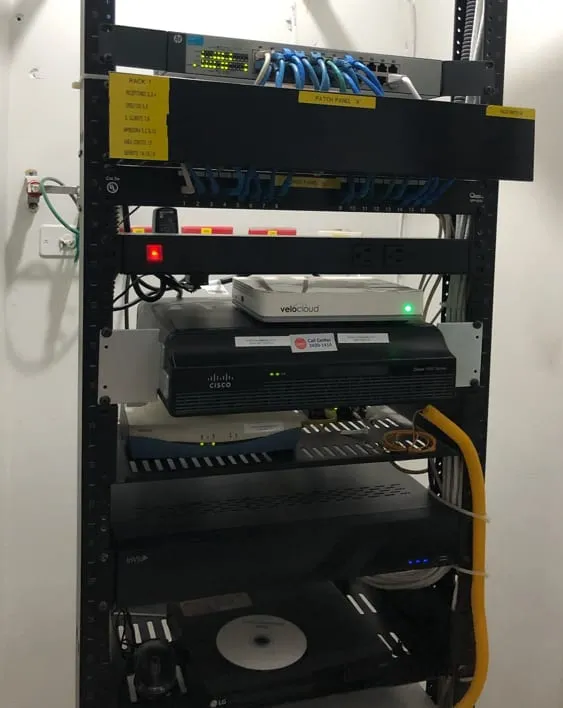 Rack de comunicaciones con switch, equipos de red y cable amarillo